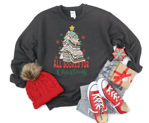 All Booked for Christmas crewneck featuring a design with books stacked in the shape of a Christmas tree, perfect for book lovers celebrating the holiday season.