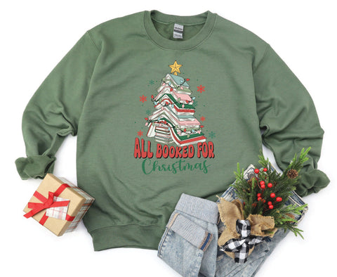 All Booked for Christmas crewneck featuring a design with books stacked in the shape of a Christmas tree, perfect for book lovers celebrating the holiday season.