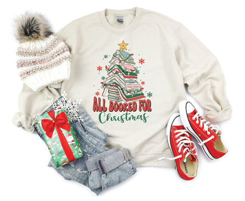 All Booked for Christmas crewneck featuring a design with books stacked in the shape of a Christmas tree, perfect for book lovers celebrating the holiday season.