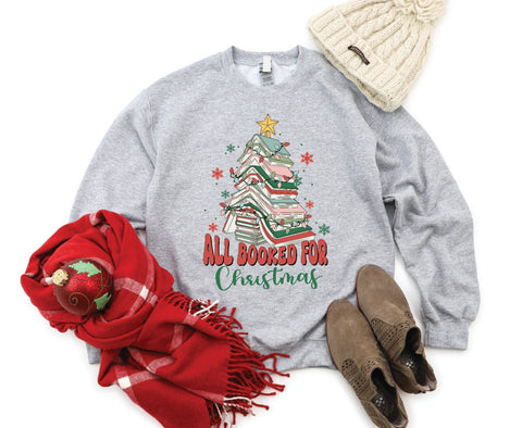 All Booked for Christmas crewneck featuring a design with books stacked in the shape of a Christmas tree, perfect for book lovers celebrating the holiday season.